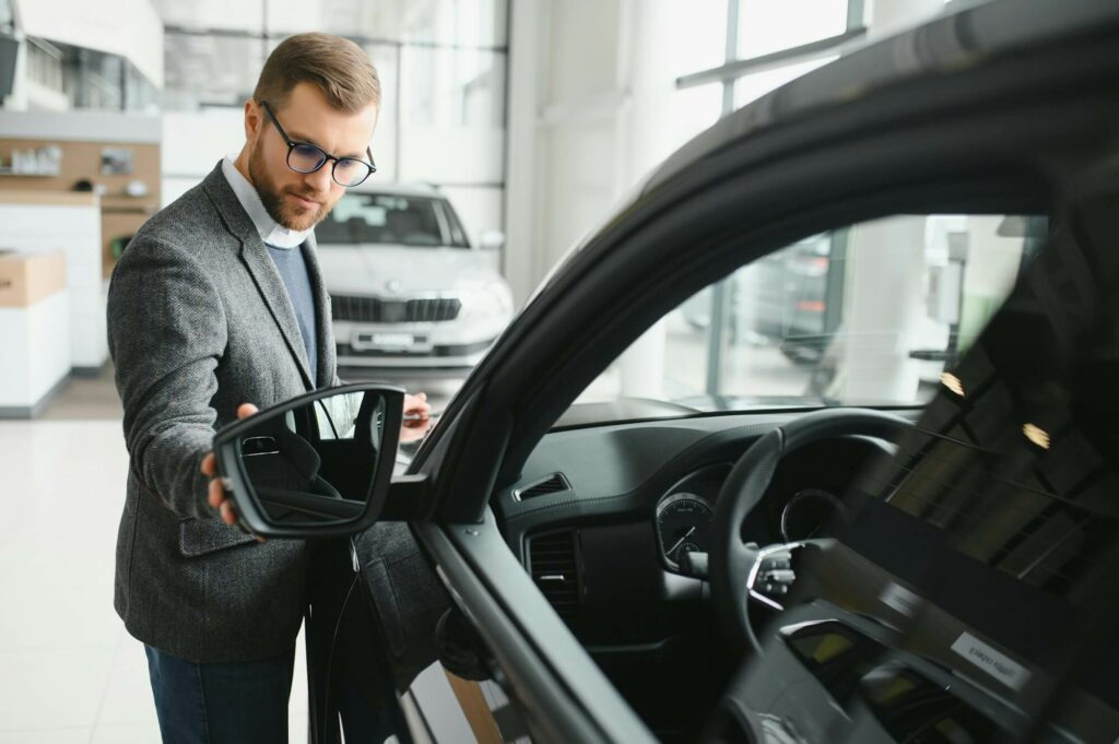 visiting car dealership handsome bearded man is stroking his new car and smiling